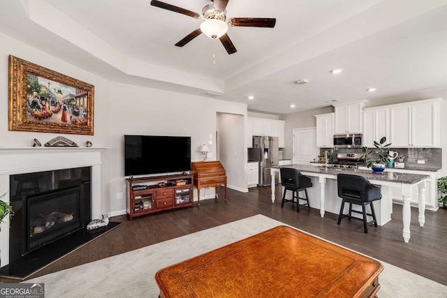 2910 Bishopstone Way, Cumming, GA 30040 - living room with ceiling fan, a glass covered fireplace, recessed lighting, dark wood-style flooring, and baseboards