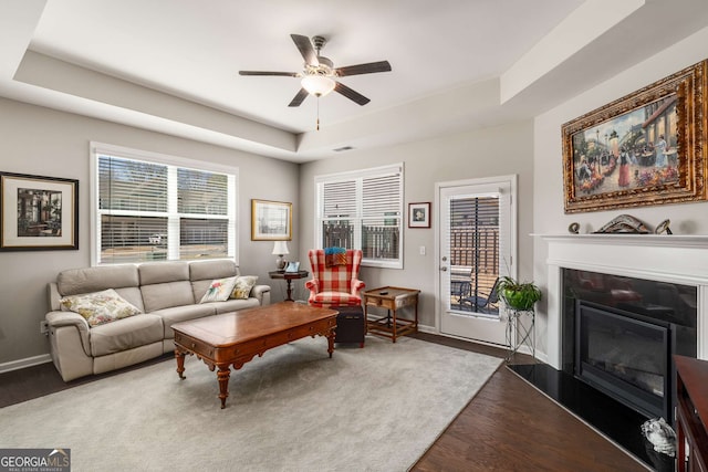 2910 Bishopstone Way, Cumming, GA 30040 - living room with ceiling fan, a glass covered fireplace, wood finished floors, a healthy amount of sunlight, and a raised ceiling