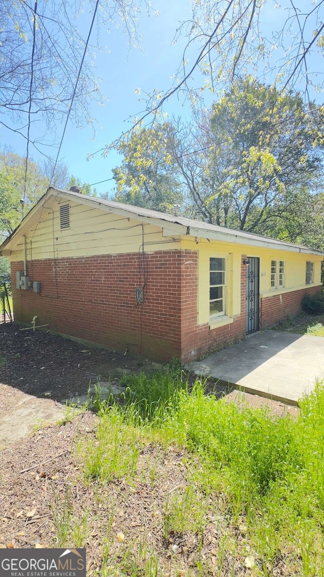 view of home's exterior with brick siding and a patio area