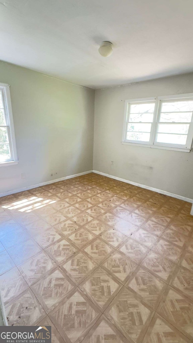 unfurnished room with baseboards, a healthy amount of sunlight, and light floors
