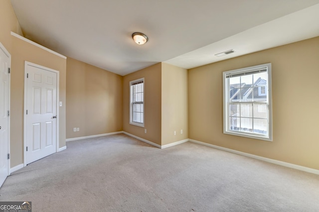 unfurnished room with baseboards, visible vents, and plenty of natural light