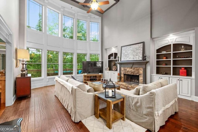 1521 Waterside Ct, Jefferson, GA 30549 - living room featuring a towering ceiling, ceiling fan, a stone fireplace, built in features, and hardwood / wood-style flooring