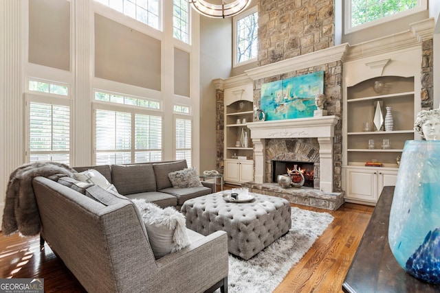 150 Inwood Ter, Roswell, GA 30075 - living room with a fireplace, a towering ceiling, wood finished floors, a notable chandelier, and built in shelves