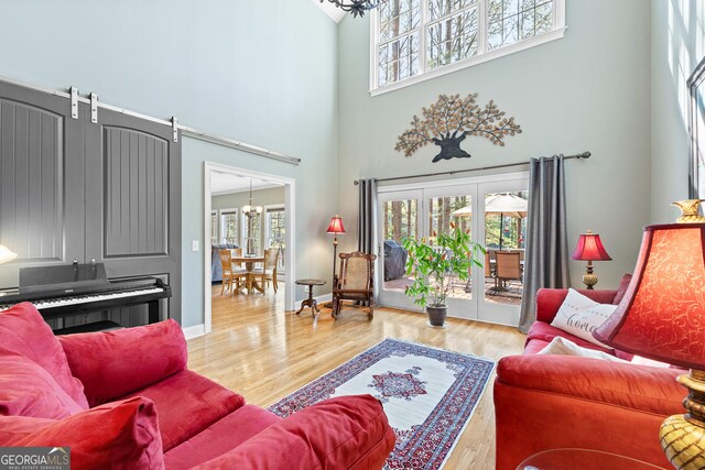 404 Golden Delicious Rd, Clarkesville, GA 30523 - living room featuring a barn door, a high ceiling, wood finished floors, baseboards, and a notable chandelier