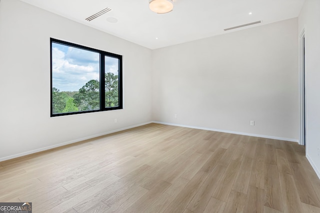 spare room featuring baseboards, visible vents, and light wood-style flooring