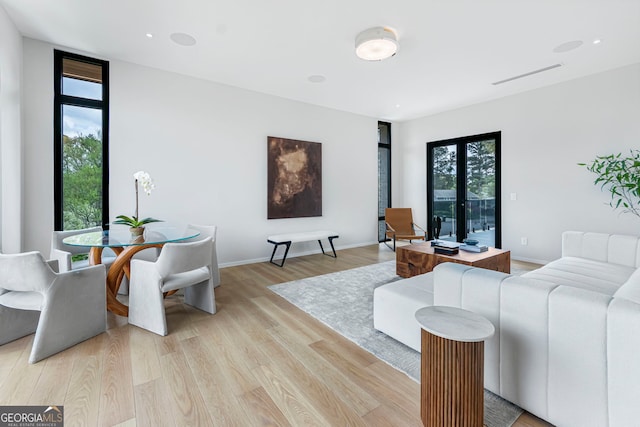 living room featuring light wood-style floors, visible vents, and baseboards