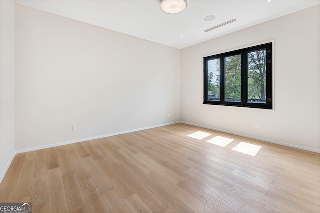 empty room with baseboards, light wood finished floors, and visible vents