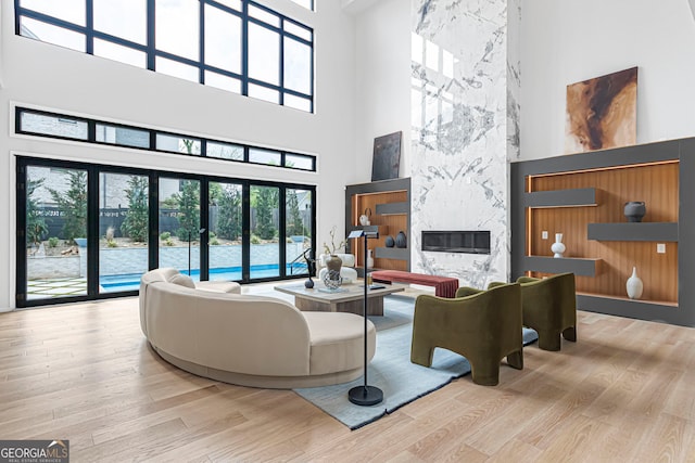 living room with wood finished floors, a towering ceiling, and a healthy amount of sunlight