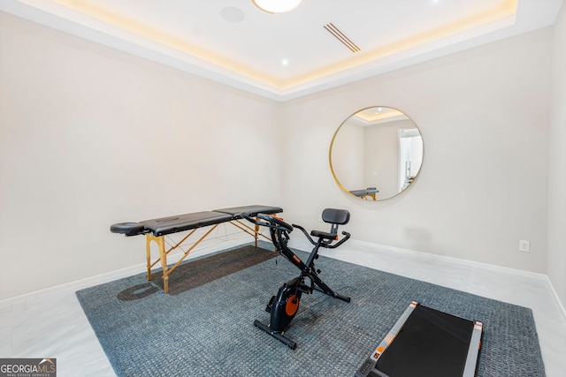 exercise room with visible vents, baseboards, and a raised ceiling