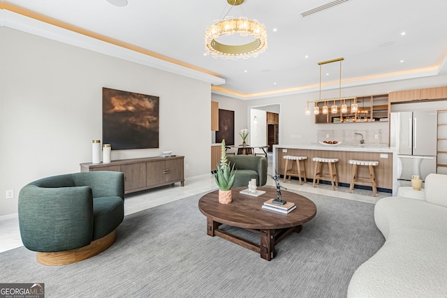 living room featuring an inviting chandelier, a raised ceiling, visible vents, bar area, and baseboards