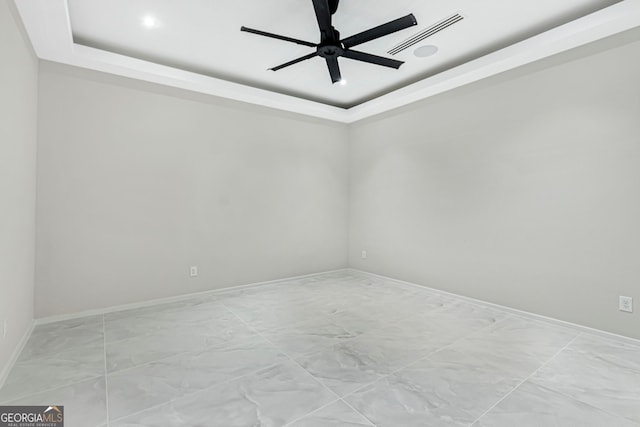 unfurnished room featuring a tray ceiling, baseboards, visible vents, marble finish floor, and ceiling fan