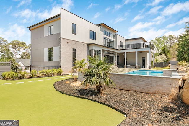 back of house featuring a ceiling fan, a fenced in pool, a balcony, a patio, and brick siding