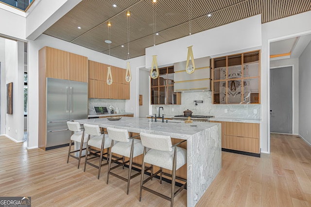 kitchen with light wood-style floors, a spacious island, decorative backsplash, and stainless steel appliances