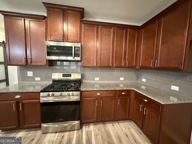 2460 Laurel Gate Ln, Cumming, GA 30040 - kitchen with dark stone counters, a sink, light wood-type flooring, visible vents, and appliances with stainless steel finishes