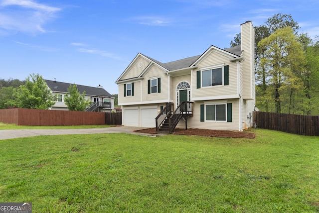 split foyer home with concrete driveway, a chimney, a front yard, a garage, and fence