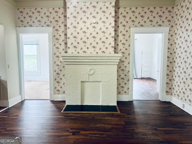 unfurnished living room featuring baseboards, wallpapered walls, and wood finished floors