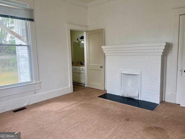 unfurnished living room featuring visible vents, ornamental molding, carpet, and a brick fireplace