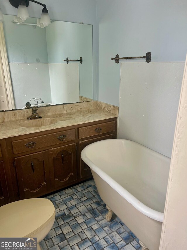 full bath with toilet, vanity, and a freestanding bath