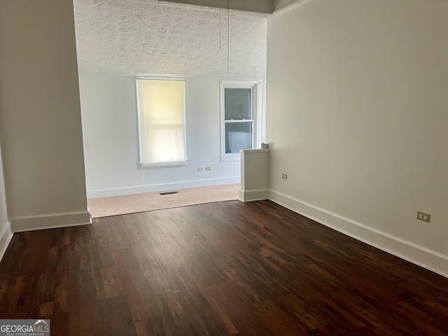 unfurnished room with dark wood finished floors, baseboards, and visible vents