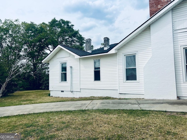 view of side of home with a lawn, a chimney, and crawl space