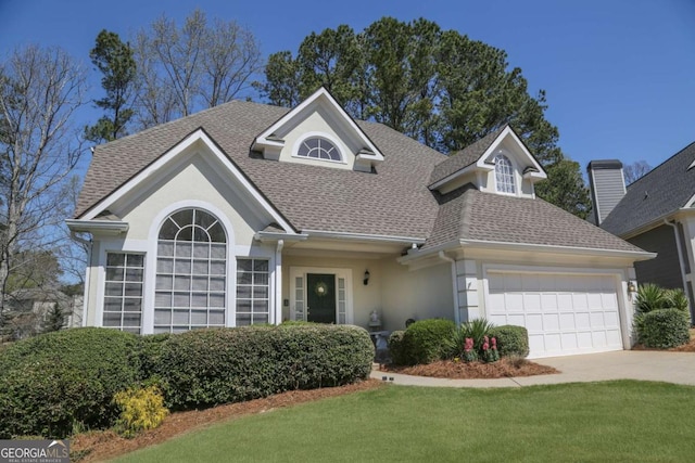 traditional-style house with a front yard, a shingled roof, stucco siding, driveway, and an attached garage
