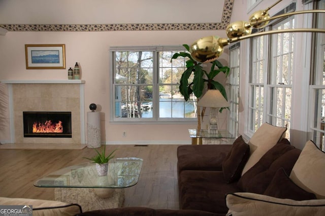 living area featuring a tile fireplace, wood finished floors, visible vents, and baseboards