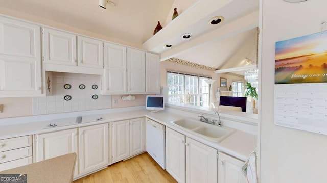 kitchen with vaulted ceiling, dishwasher, light countertops, and a sink