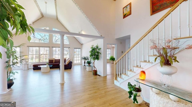 entryway with stairway, wood finished floors, and high vaulted ceiling
