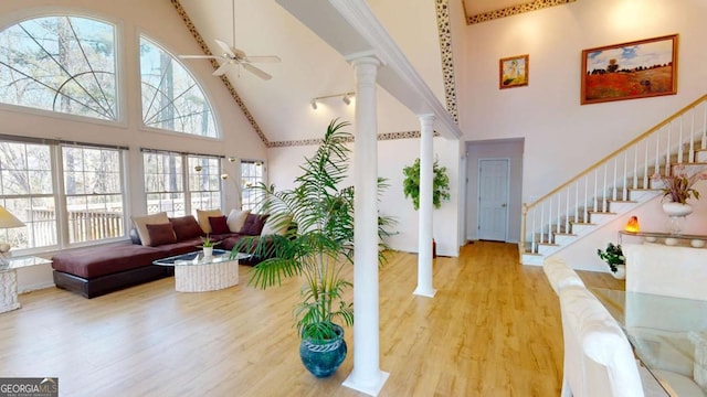 interior space featuring a towering ceiling, wood finished floors, decorative columns, and a wealth of natural light