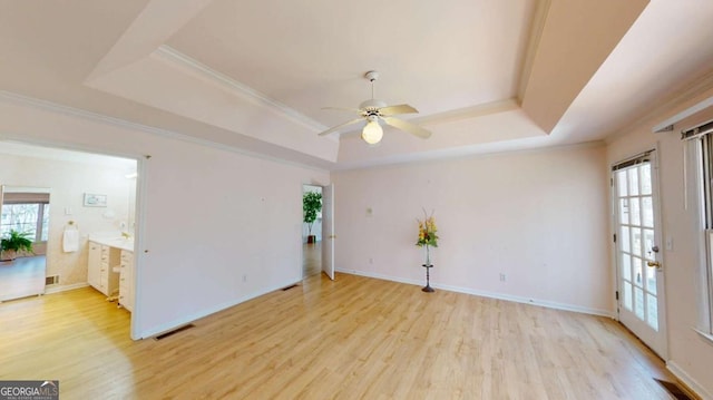 unfurnished room with visible vents, a raised ceiling, a healthy amount of sunlight, and a ceiling fan