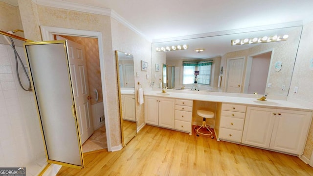 bathroom featuring crown molding, double vanity, a sink, and wood finished floors