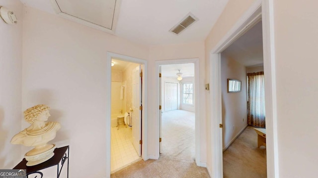 corridor featuring baseboards, visible vents, and light carpet