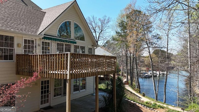 back of house with a patio, a deck with water view, and a shingled roof