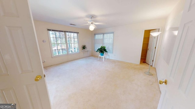 empty room with visible vents, a ceiling fan, and carpet floors