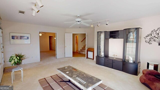 living area with visible vents, light carpet, track lighting, a ceiling fan, and stairs