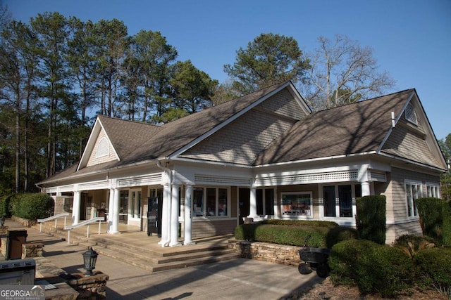 rear view of house featuring a patio and roof with shingles