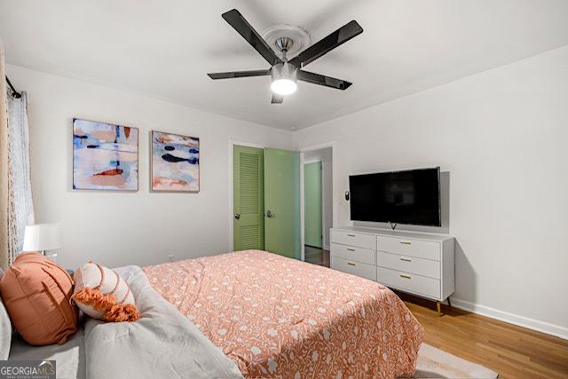 bedroom featuring a ceiling fan, baseboards, and light wood-style floors