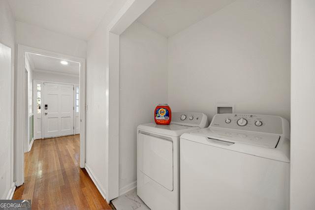 washroom featuring light wood-style flooring, washer and clothes dryer, baseboards, and laundry area