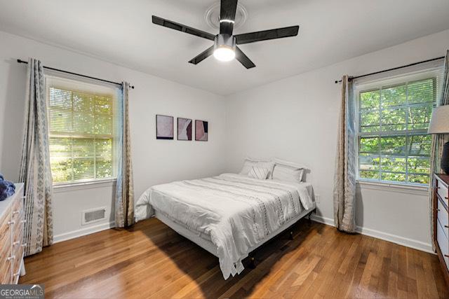 bedroom featuring a ceiling fan, wood finished floors, baseboards, and visible vents