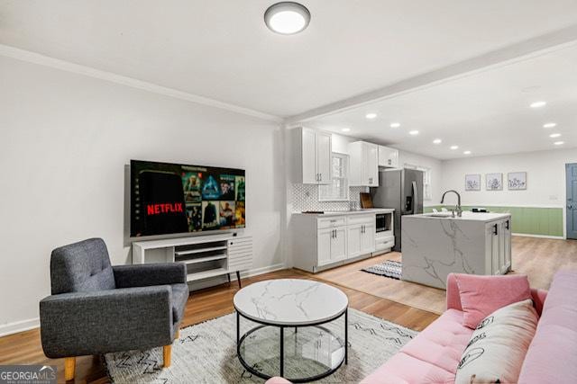 living room featuring baseboards, crown molding, light wood-style floors, and recessed lighting
