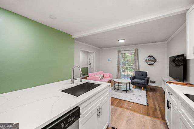 kitchen with white cabinets, light wood-style flooring, dishwasher, a sink, and open floor plan