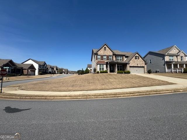 5530 Lacebark Pine Ct, Cumming, GA 30040 - view of front of house with a residential view, concrete driveway, stone siding, and an attached garage
