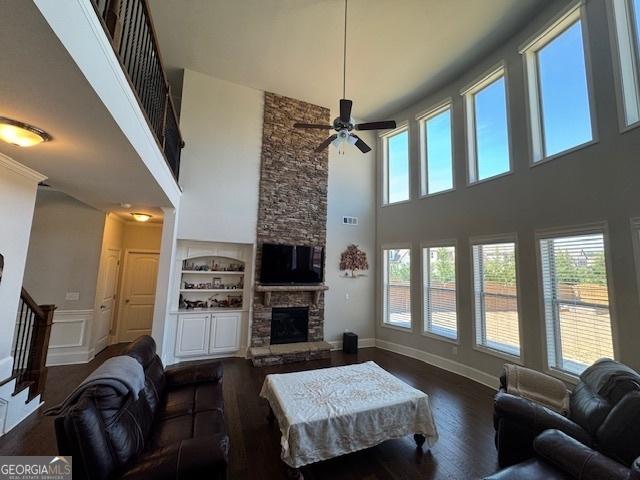 5530 Lacebark Pine Ct, Cumming, GA 30040 - living room featuring a high ceiling, built in features, a fireplace, wood finished floors, and a ceiling fan