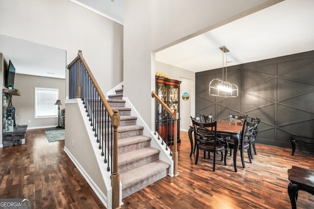 stairs with baseboards, a high ceiling, wood finished floors, and a chandelier