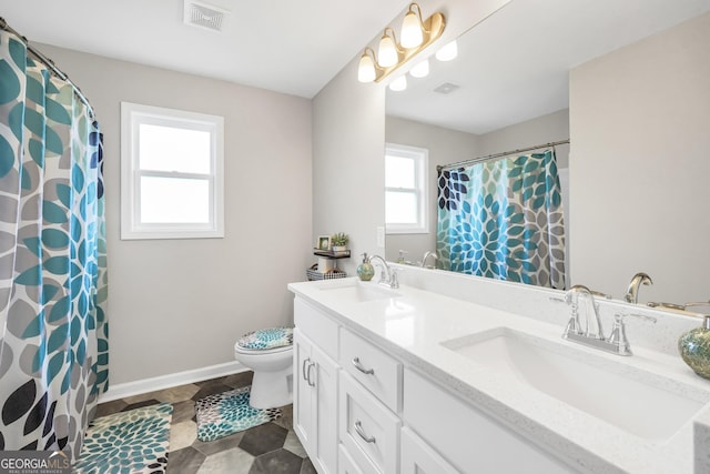 bathroom featuring double vanity, toilet, visible vents, and a sink