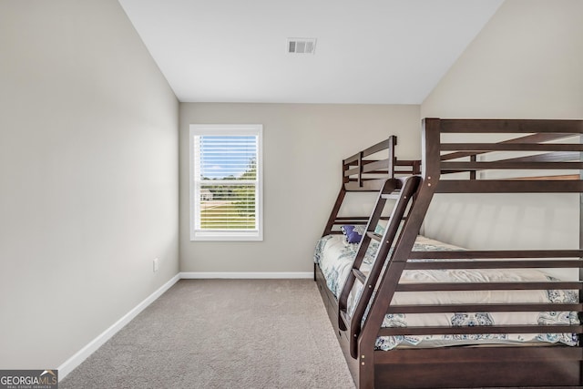unfurnished bedroom with carpet floors, baseboards, lofted ceiling, and visible vents