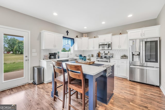 kitchen featuring light countertops, decorative backsplash, stainless steel appliances, and white cabinetry