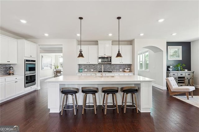 kitchen with dark wood finished floors, decorative backsplash, stainless steel appliances, and light countertops