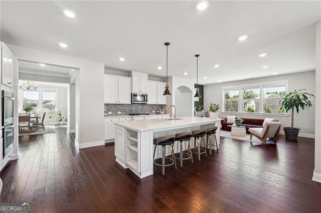 kitchen featuring light countertops, a sink, stainless steel microwave, and dark wood finished floors
