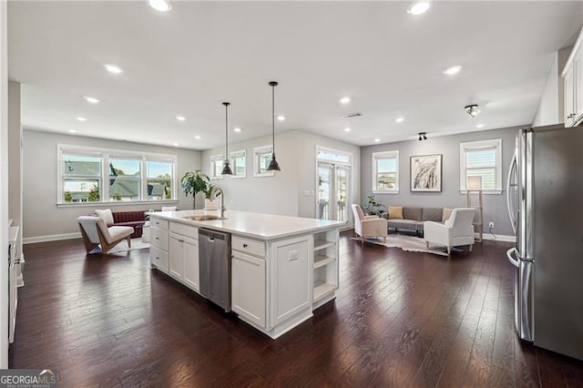 kitchen with white cabinets, baseboards, appliances with stainless steel finishes, and open floor plan